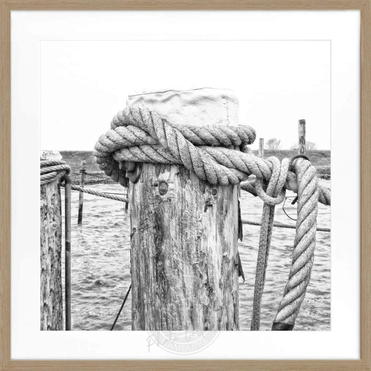 Schwarz-weißes Poster mit Rahmen von Cosman-Photocollection, zeigt das Motiv ‘Poller’ Rantum Sylt, quadratisch 55x55cm.