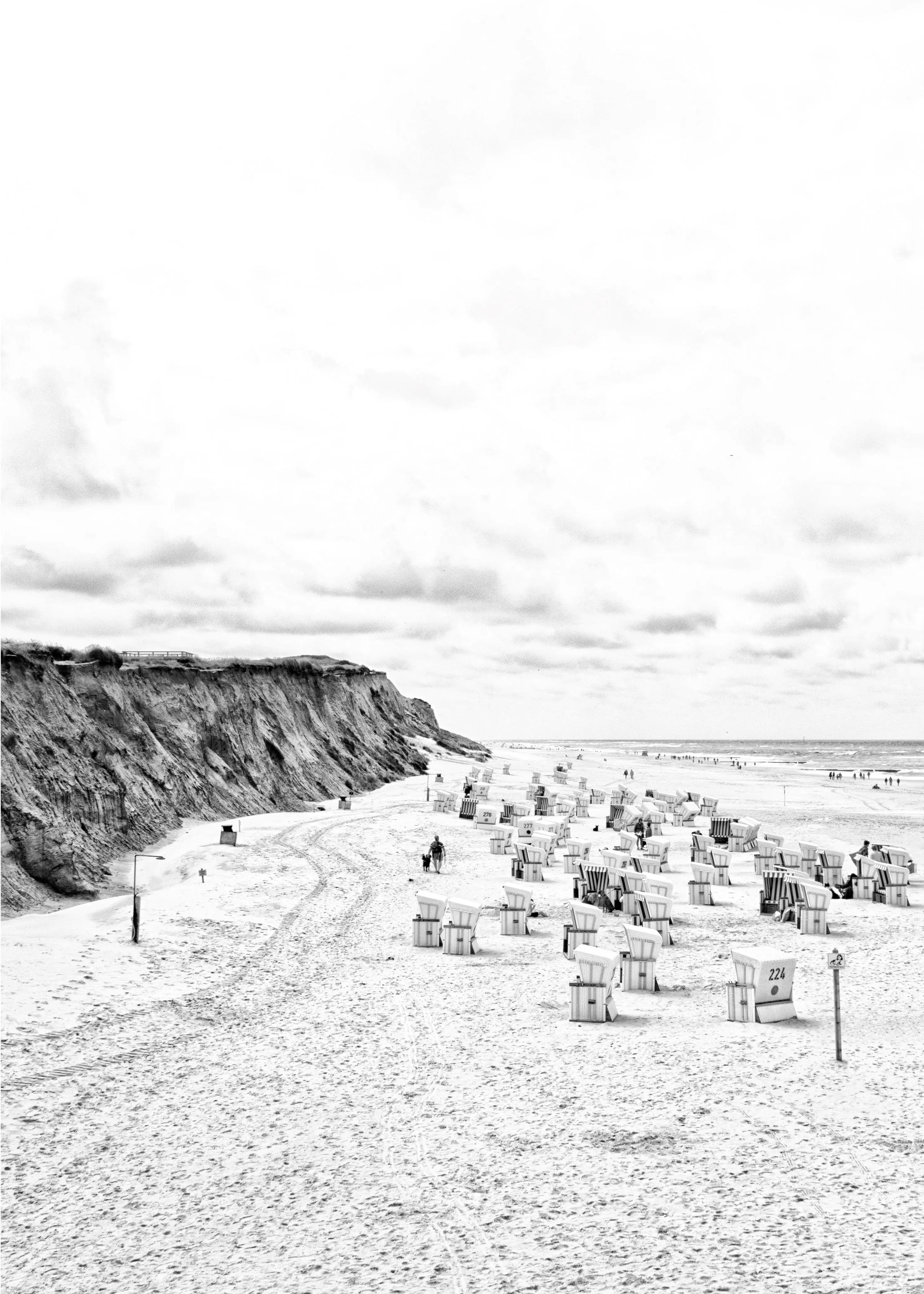 Sylt Strandkörbe Poster mit Strandkörben an der Nordsee und Klippen im Hintergrund, schwarz-weiß Bild.