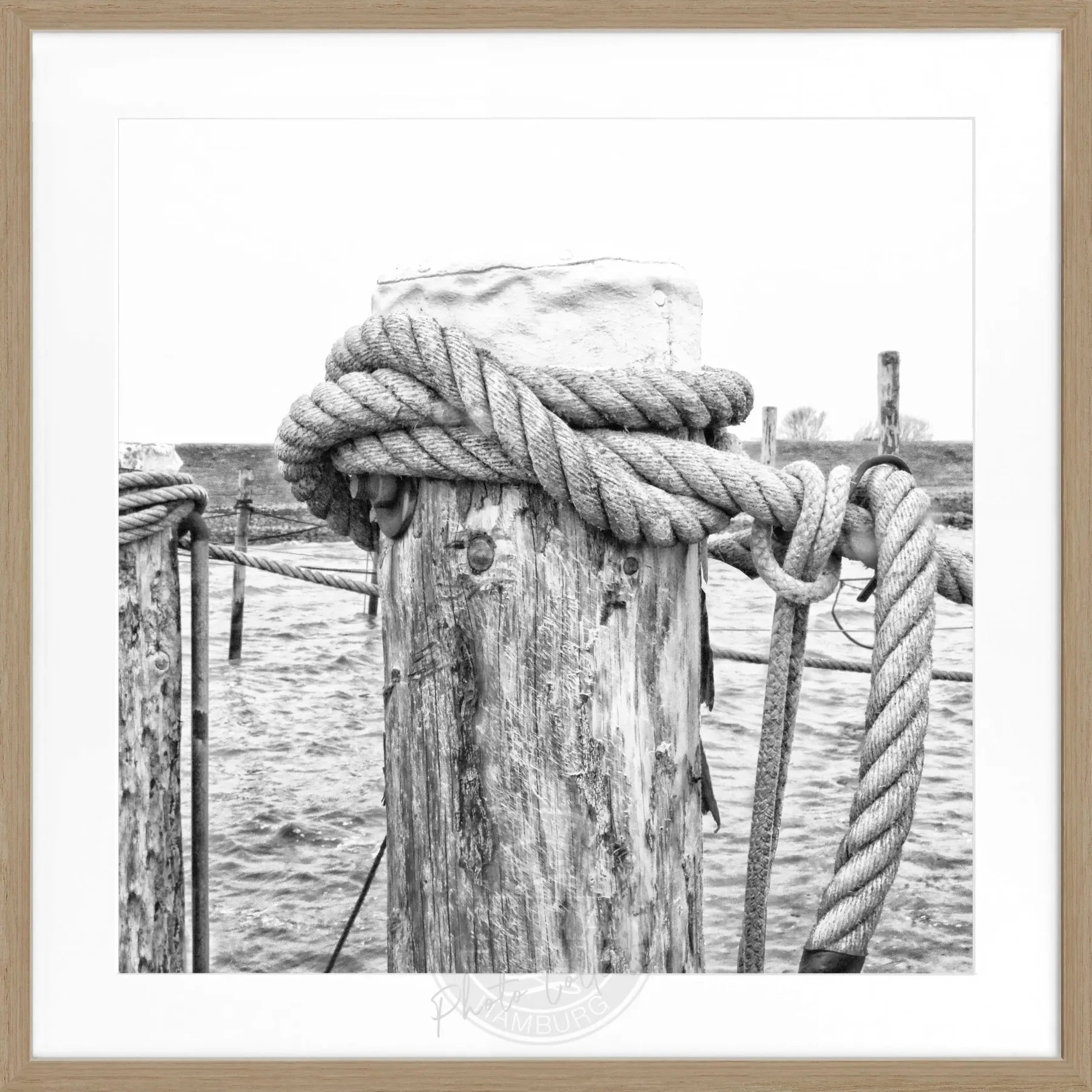 Schwarz-weißes Poster mit Rahmen von Cosman-Photocollection, zeigt das Motiv ‘Poller’ Rantum Sylt, quadratisch 55x55cm.